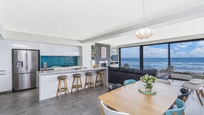 A modern kitchen with a large island, bar stools, and a view of the ocean. - Aqua Mist Seascape - refreshing ocean-views (Port Fairy)