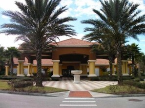 A hotel entrance with a tiled roof, palm trees, and a central pathway leading to the entrance. - Encantada Townhome with Private Pool - EC001 (Kissimmee)