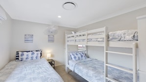 A room with bunk beds, a bedside table with a lamp, and wall art depicting a beach scene.