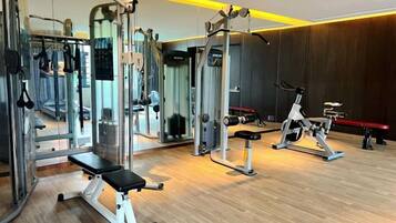 A gym with various exercise equipment, including a bench, weight machines, and a rowing machine.