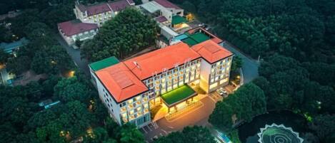 An aerial view of a hotel with multiple buildings, surrounded by dense greenery.
