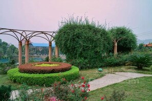 A garden with a circular flower bed, a pergola, and a pathway.