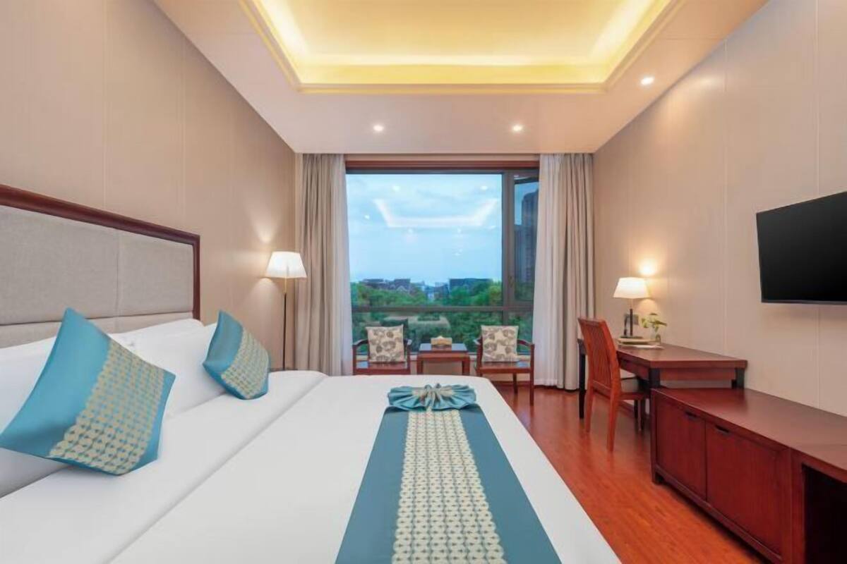 A hotel room with a bed, a desk, a chair, and a TV.