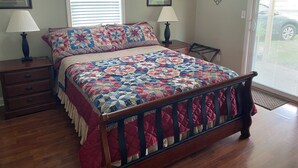 A bedroom with a wooden bed, two bedside tables with lamps, a window with blinds, and a wall decoration.