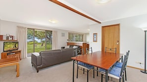 Relax in this inviting living room with a garden view, featuring a sofa, dining table, and TV.