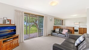 Enjoy a comfortable stay in this well-appointed living space with a large window offering a view of the outdoors, a flat-screen TV, and a cozy sofa.
