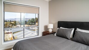 Relax in a spacious room with a large bed, nightstand, and window offering a view of the coastal landscape.