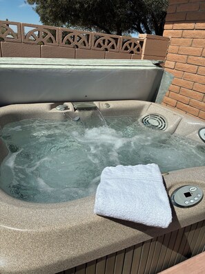 Ein Whirlpool mit Bedienfeld, ein Handtuch und eine Ziegelwand im Hintergrund.