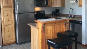 A kitchen with wooden cabinets, a stainless steel refrigerator, a microwave, an oven, a coffee maker, and a sink. - Guesthouse, with quail, cactus, & desert. (Florence)