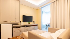 A modern hotel room with a bed, a desk, a television, and a mini-fridge. - 100m from the Avenue. Paulista / 30m from the shopping mall / close to the subway and hospitals (Bela Vista)