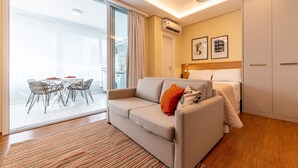 A modern living room with a sofa, a dining area with chairs, and a bed with a headboard. - 100m from the Avenue. Paulista / 30m from the shopping mall / close to the subway and hospitals (Bela Vista)