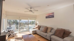 Ein geräumiges Wohnzimmer mit einer großen Eckcouch, einem Holztisch und einem Deckenventilator.