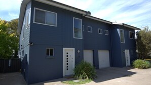 Ein zweistöckiges Wohnhaus mit dunkelblauer Fassade, weißen Verzierungen und einer Garage mit zwei Toren.