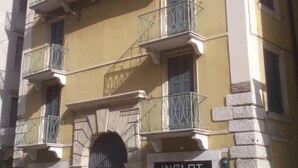 Un edifici de diverses plantes amb façana groga, múltiples balcons amb baranes de metall i una botiga amb el rètol "INGLOT".