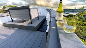 A deck with a bench, a bottle of Inama Vin Soave, and two glasses of wine.