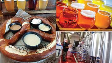 Un pretzel con salsas para mojar, varias cervezas y una cervecería.