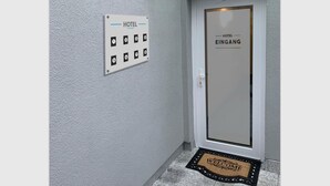 A hotel entrance with a numbered keypad door, a welcome mat, and a glass panel above the door. - Hotel Am Spielacker (Gelnhausen)