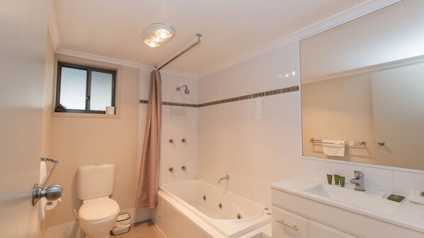 A bathroom with a toilet, bathtub, shower, and a large mirror.