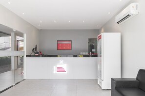 A modern reception area with a glass partition, a digital display, and a seating area. - Mega Aeroporto Hotel (Fortaleza)