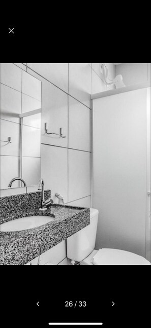 A modern bathroom with a granite countertop sink, a mirror, and a toilet. - Mega Aeroporto Hotel (Fortaleza)