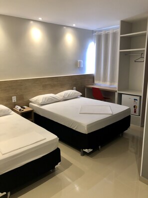 A hotel room with two beds, a desk, a wardrobe, and a minibar.
