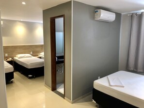 A hotel room with two beds, a bathroom with a mirror, and an air conditioning unit. - Mega Aeroporto Hotel (Fortaleza)
