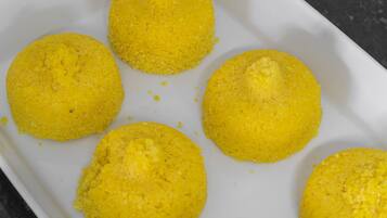 A white rectangular tray with six yellow, round, breaded items.