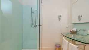 A modern bathroom with a glass shower enclosure, a glass sink with a marble countertop, and a white vanity with a mirror above. - Wytonia 1 - Spectacular Ocean Views (Port Fairy)