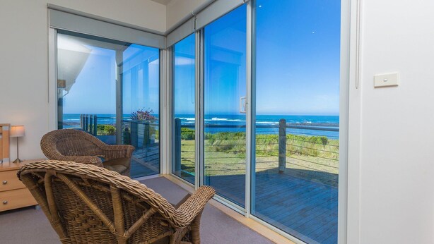 A balcony with a view of the ocean, wicker chairs, and a wooden table. - Wytonia 1 - Spectacular Ocean Views (Port Fairy)