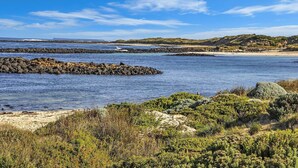 A coastal landscape with rocky outcrops, sandy beaches, and green vegetation. - Hearns Beachside Villa 4 (Port Fairy)