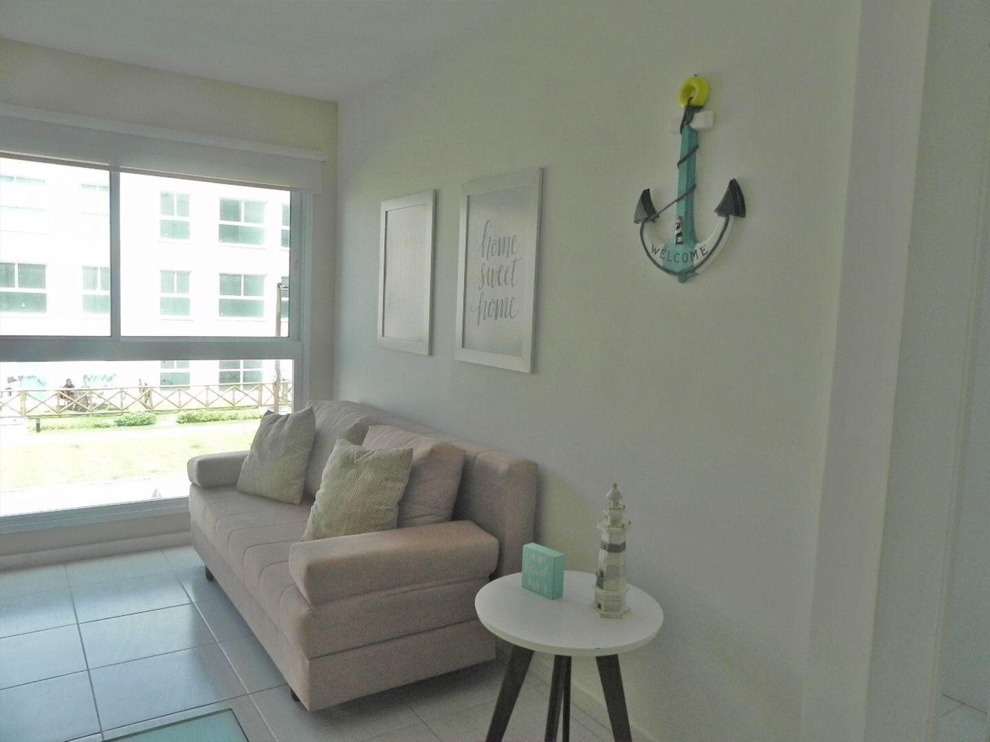 A room with a beige sofa, a small white table, and a decorative wall piece.