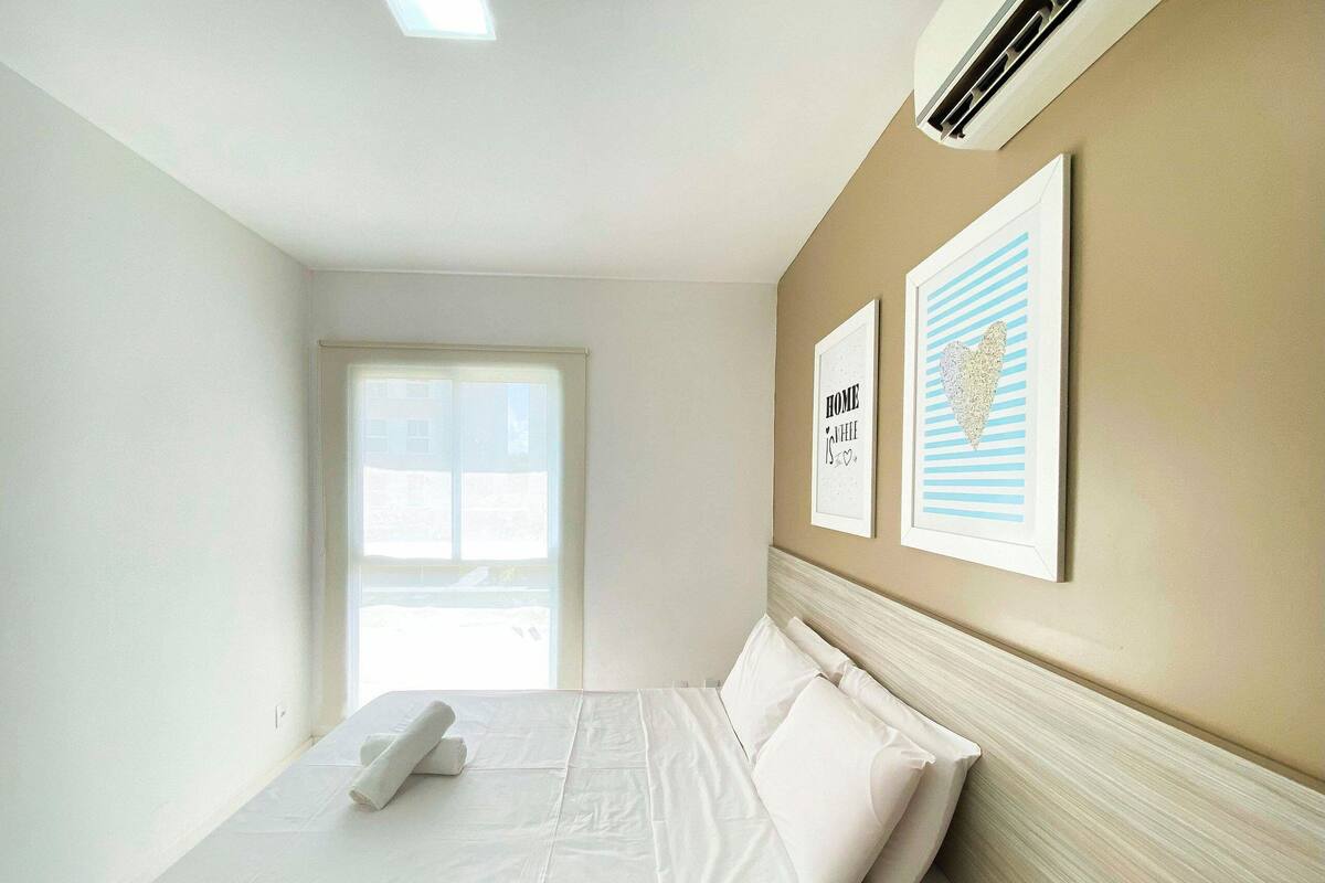 A hotel room with a bed, a window, and two framed pictures on the wall.
