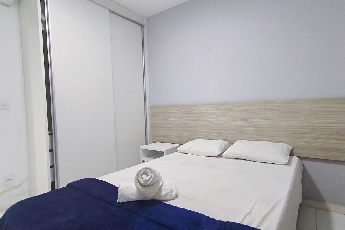 A hotel room with a bed, a nightstand, and a wooden headboard.
