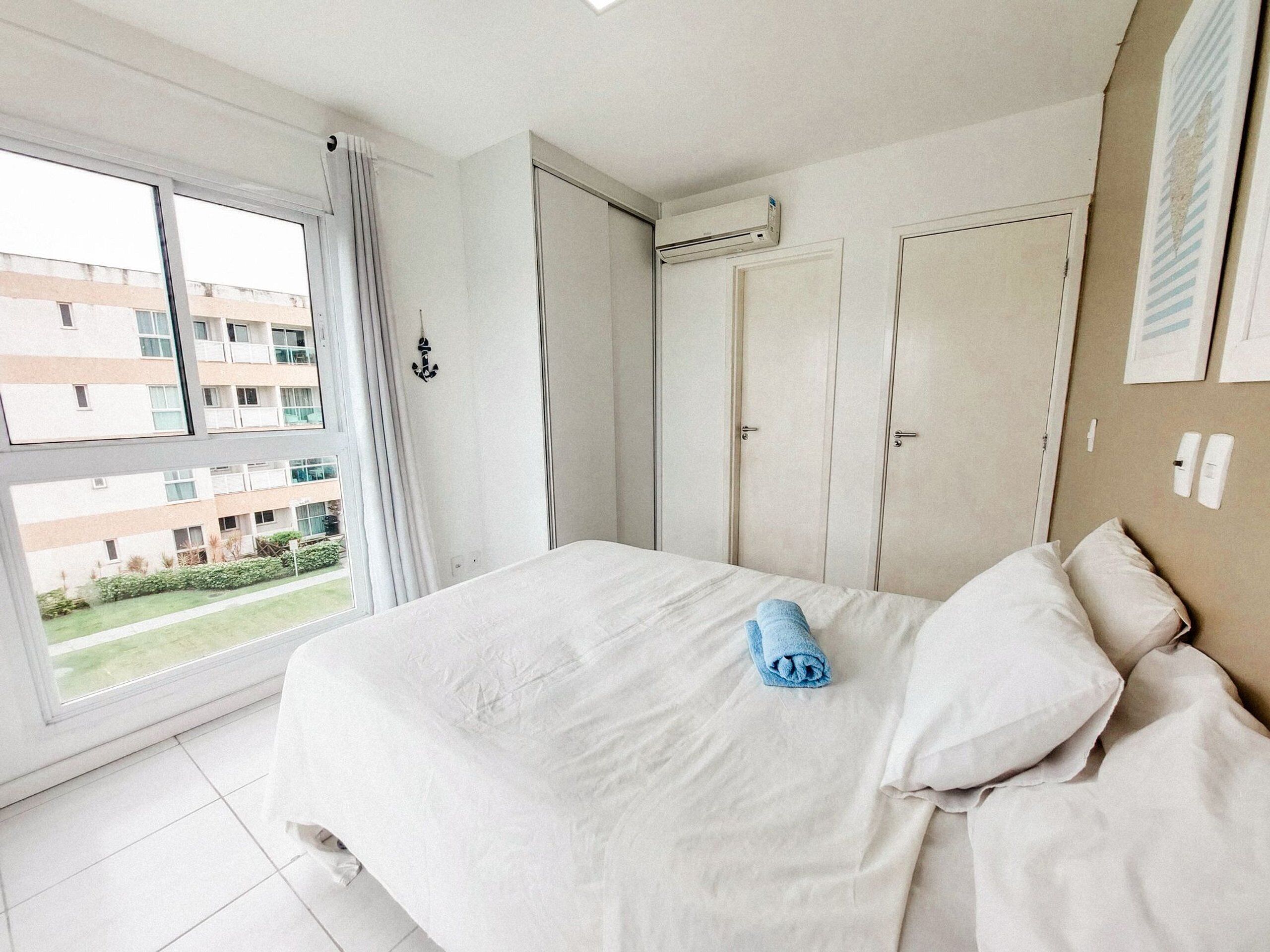Una habitación de hotel con una cama grande, una ventana con cortinas, un armario y un equipo de aire acondicionado.