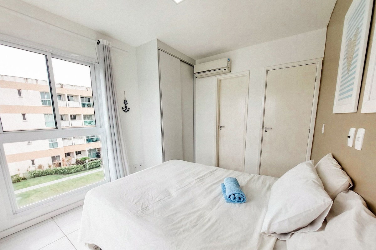 Una habitación de hotel con una cama grande, una ventana con cortinas, un armario y un equipo de aire acondicionado.