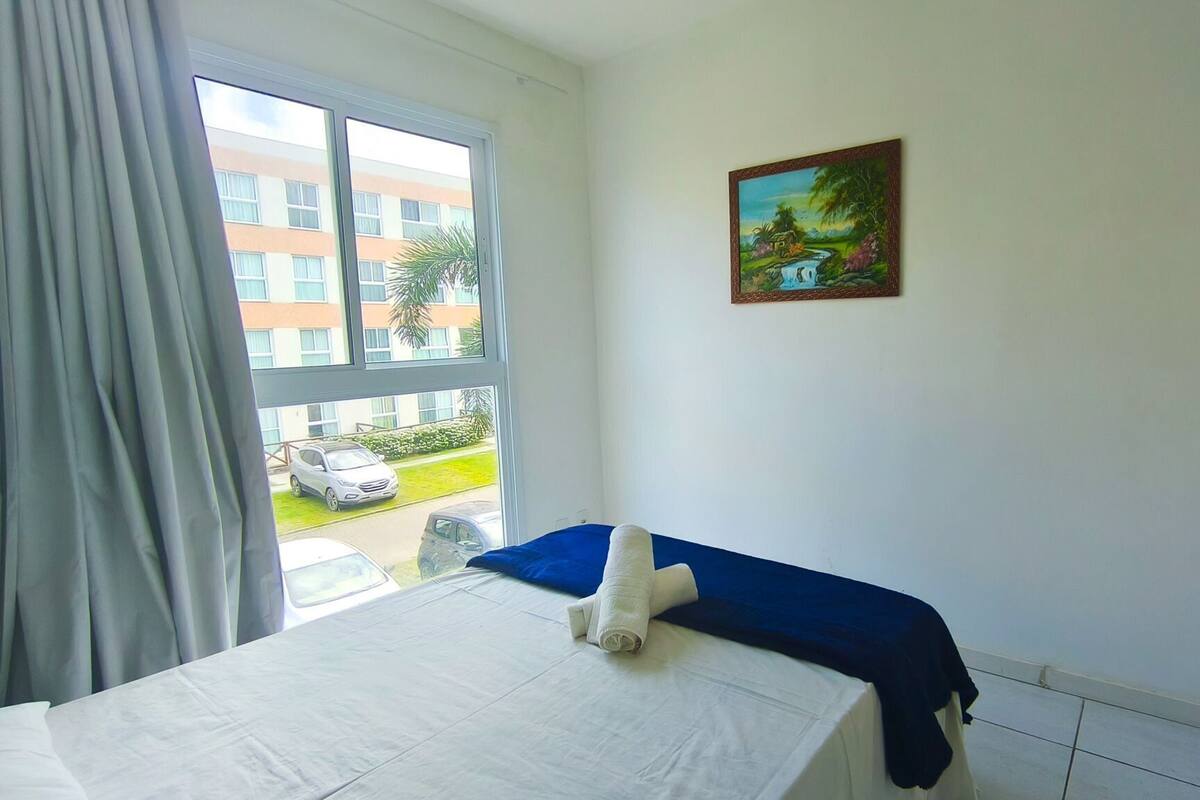 Una habitación de hotel con una cama, un ventanal con cortinas y un cuadro en la pared.