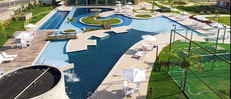 Una piscina al aire libre, sombrillas, sillones reclinables de piscina