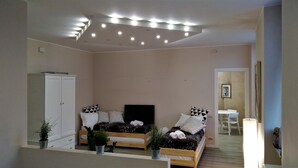 A modern bedroom with two beds, a wardrobe, and a dining area. - Marconi Rooms - Loggia delle Erbe (Verona)
