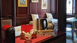 A hotel room with a wooden paneled wall, a bed with pillows, a coffee table with tea-related items, and framed pictures on the wall. - Marconi Rooms - Loggia delle Erbe (Verona)