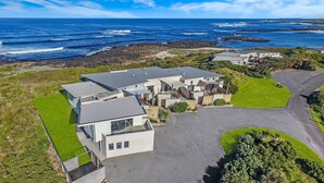 A modern residential area with multiple houses, a paved driveway, and a view of the ocean. - Hearns Beachside Villa 9 (Port Fairy)