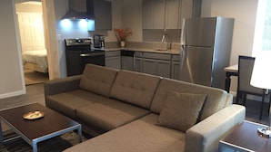 A modern kitchen with stainless steel appliances, a sofa, and a dining area.