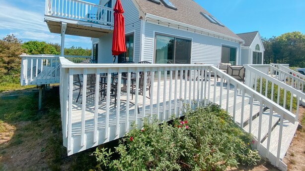 A two-story house with a white exterior, a balcony, and a covered patio area. - NEWLY RENOVATED, LARGE, SERENE, SUNNY  HOME ON PRIVATE ROAD (North Truro)
