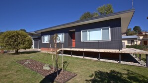A modern two-story house with a flat roof, large windows, and a small front porch.