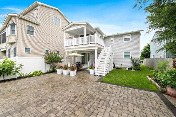 A two-story house with a balcony, a covered patio, and a well-maintained lawn.