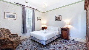 Une chambre à coucher avec un lit, deux lampes de chevet, une chaise et un tapis à motifs floraux.