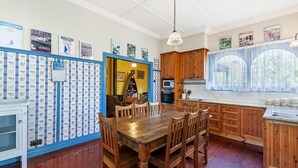 Une cuisine avec des meubles de rangement en bois, une table à manger avec des chaises, un four à micro-ondes et une fenêtre avec des rideaux.