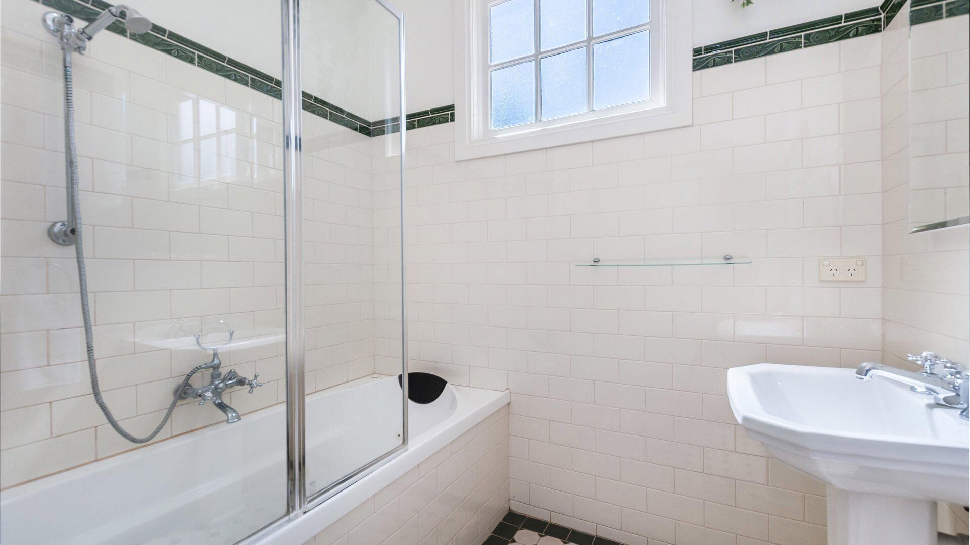 Een badkamer met een douche in een glazen cabine, een witte badkuip en een wastafel.