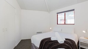 A bedroom with a bed, a window, a bedside table, and a wardrobe. - Snowdome - 4/3 Poly Cow Lane (Jindabyne)