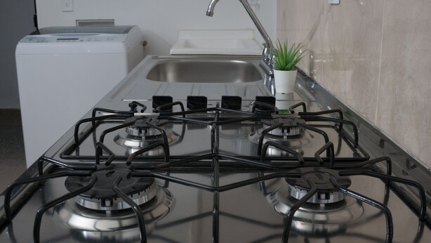 Une cuisine équipée d’une cuisinière à gaz, d’un lave-linge et d’un évier.