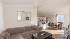 Een woonkamer met een bank, een salontafel en een eethoek met stoelen en een tafel.